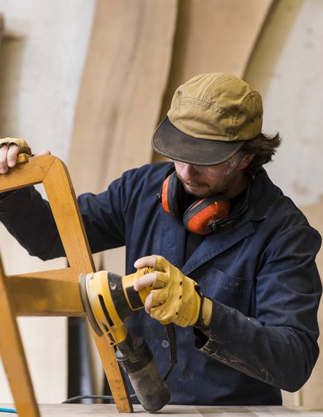 close-up-male-carpenter-sanding-furniture-with-power-tool-workbench